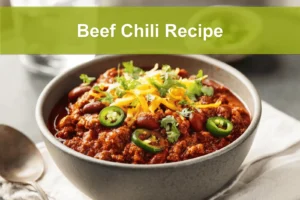 Beef Chili Recipe hearty bowl with shredded cheese fresh herbs jalapeños on white napkin