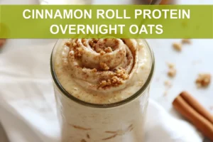 CINNAMON ROLL PROTEIN OVERNIGHT OATS jar with cinnamon swirl on white napkin beside water