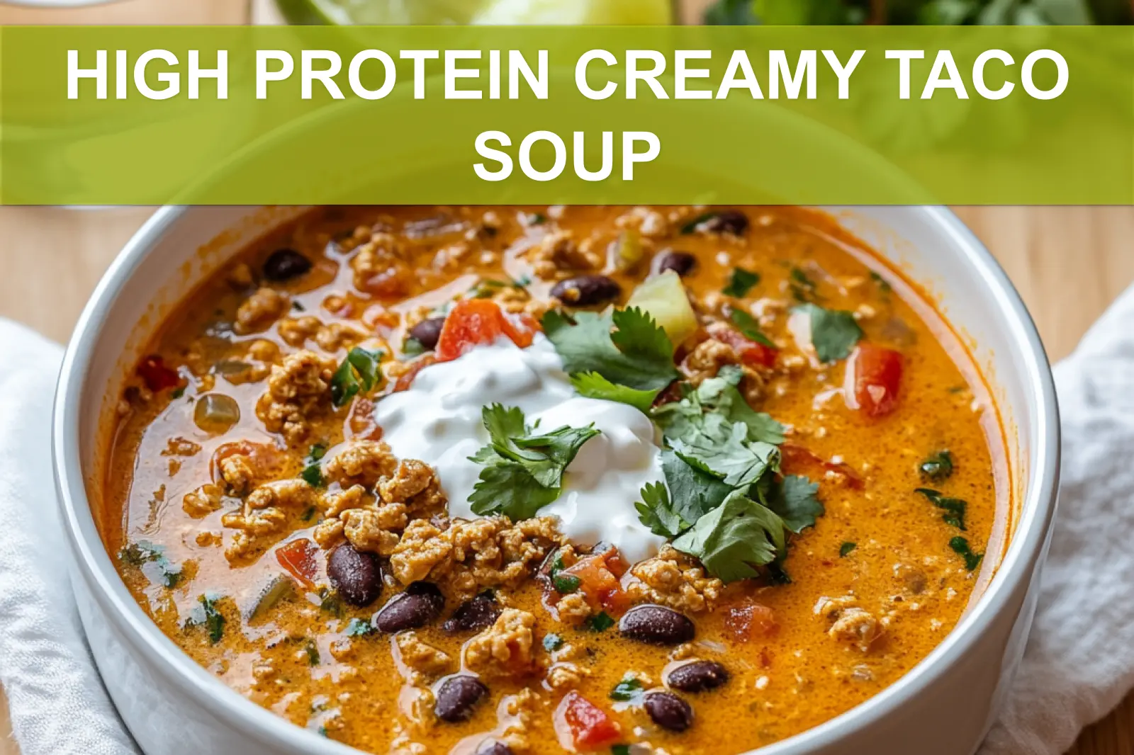 HIGH PROTEIN CREAMY TACO SOUP in bowl with herbs lime wedges and melted cheese