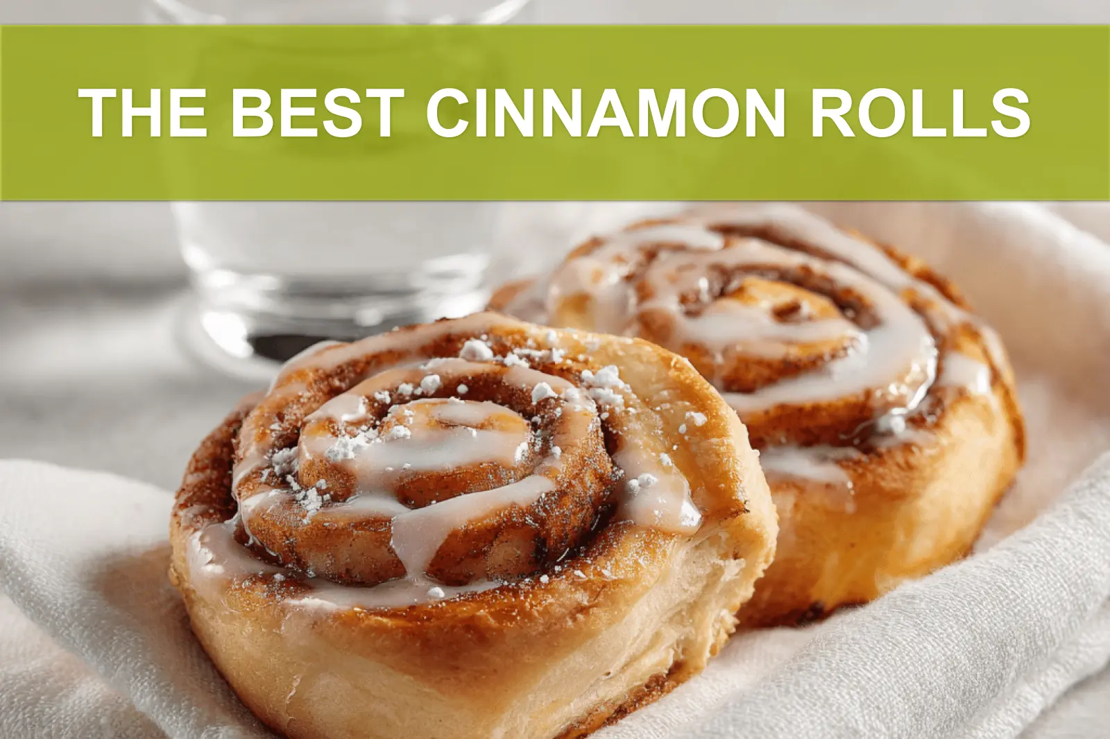 THE BEST CINNAMON ROLLS warm glazed pastries on white cloth with glass of water