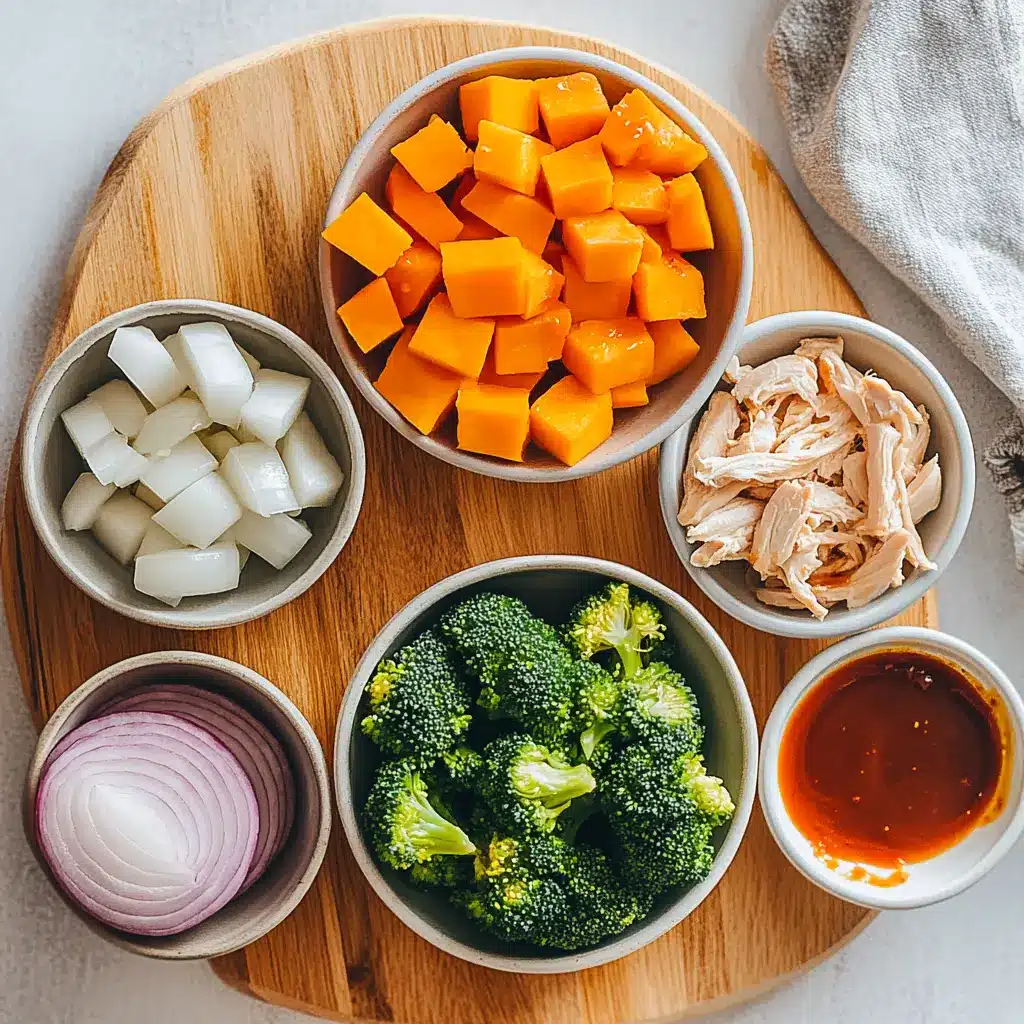 Flat lay of ingredients for BBQ Chicken Roasted Sweet Potato Bowls including sweet potatoes, BBQ sauce, chicken breasts, onions, and spices